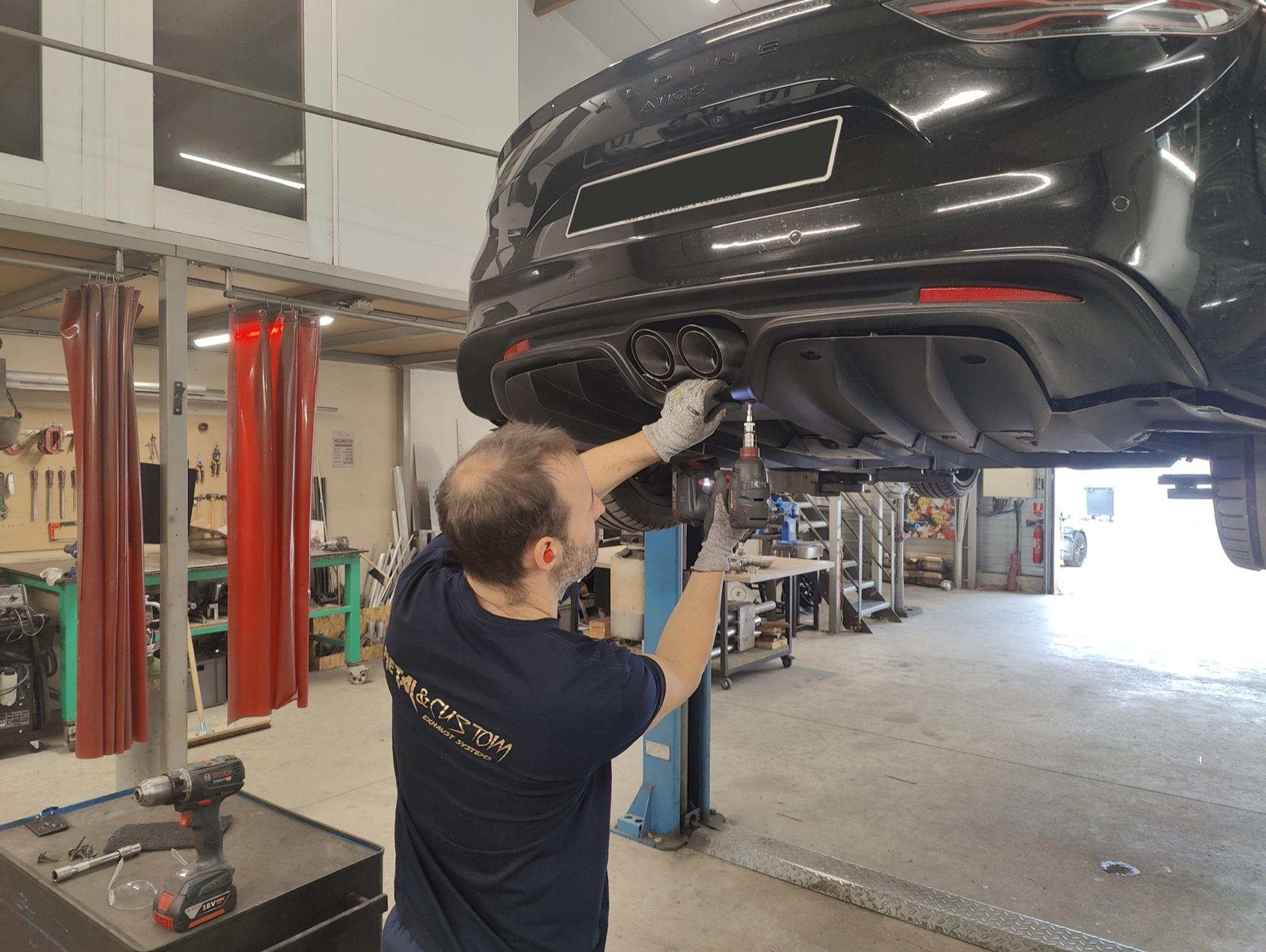 Montage d'une ligne d'échappement Metal Custom sous une Alpine A110 S levée sur pont, dans l'atelier