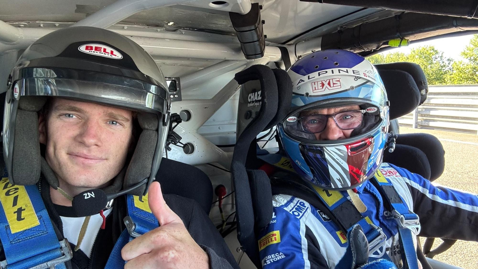 Un passager et son pilote casqués, harnachés dans une voiture de course